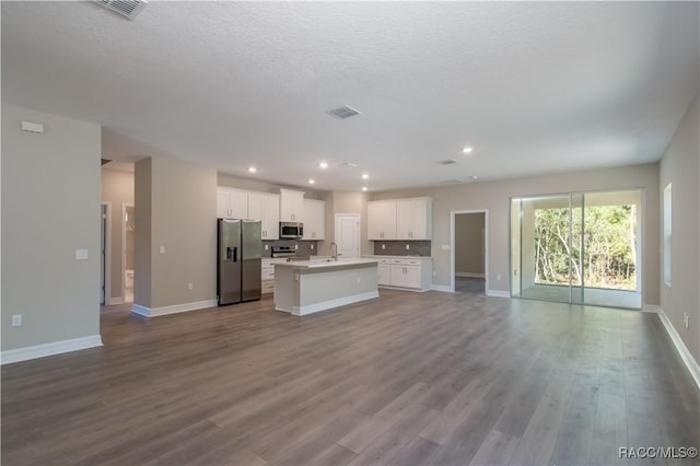 kitchen featuring stainless steel appliances, an island with sink, a textured ceiling, white cabinets, and light wood-type flooring