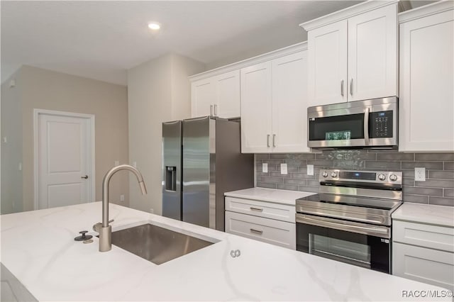 kitchen with white cabinets, decorative backsplash, sink, and stainless steel appliances