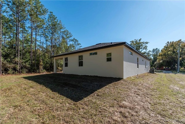 view of side of home with central air condition unit and a lawn