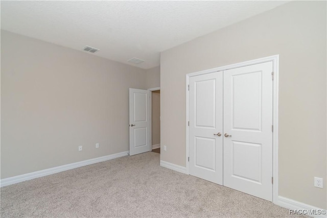 unfurnished bedroom with a closet and light colored carpet