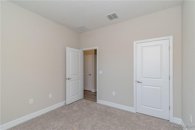 unfurnished bedroom with light carpet and a textured ceiling