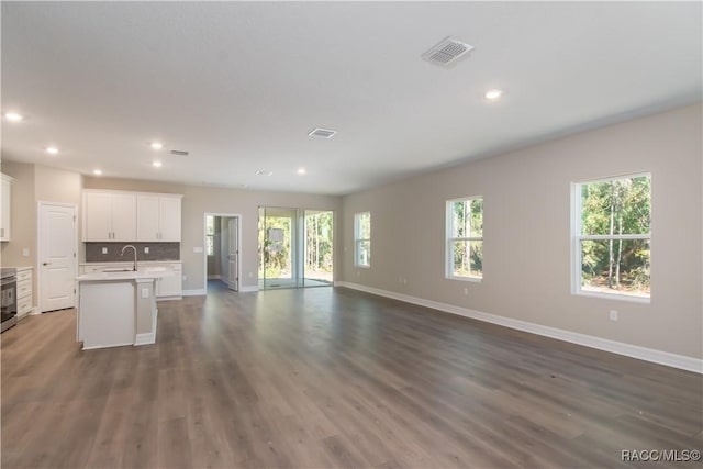 kitchen featuring stainless steel range, dark wood-type flooring, sink, a center island with sink, and white cabinets