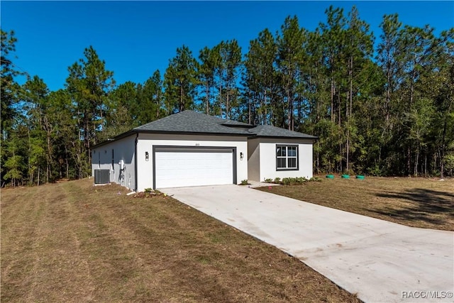 view of front facade with cooling unit, a garage, and a front lawn