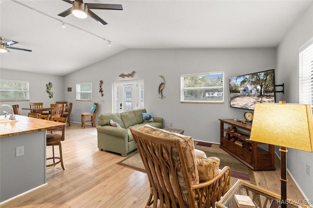 living room with ceiling fan, lofted ceiling, a healthy amount of sunlight, and light wood-type flooring