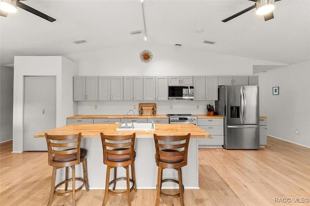 kitchen with gray cabinetry, ceiling fan, stainless steel appliances, and butcher block counters