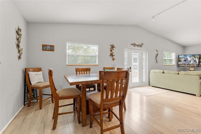 dining space featuring a wealth of natural light, lofted ceiling, and light wood-type flooring