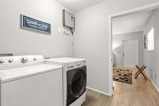 clothes washing area with washing machine and dryer and light wood-type flooring