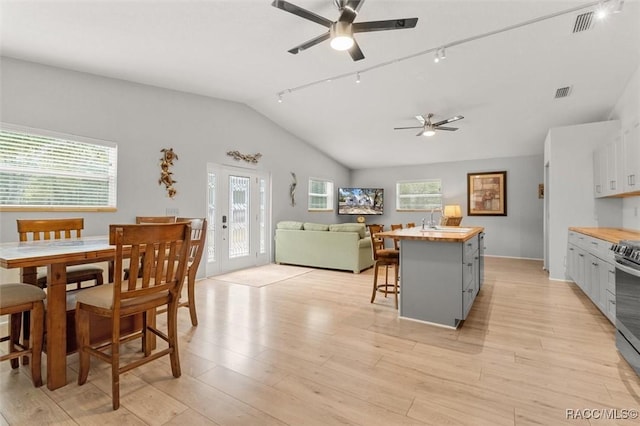 dining space featuring ceiling fan, vaulted ceiling, sink, light hardwood / wood-style flooring, and french doors