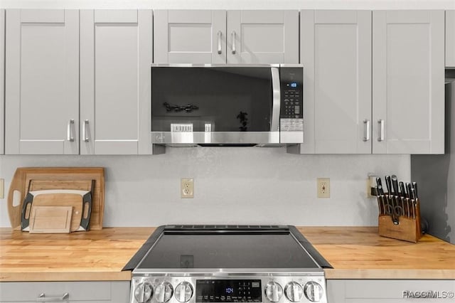 kitchen featuring butcher block counters, stainless steel appliances, and tasteful backsplash