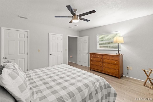 bedroom featuring ceiling fan, light wood-type flooring, and a textured ceiling