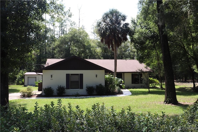 ranch-style home with a front yard, a garage, and an outdoor structure