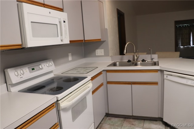 kitchen with sink, light tile patterned floors, kitchen peninsula, white appliances, and white cabinets