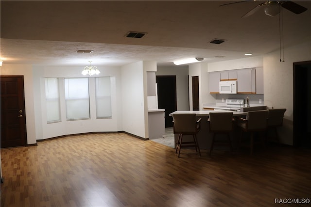 kitchen with hardwood / wood-style floors, gray cabinets, white appliances, and kitchen peninsula