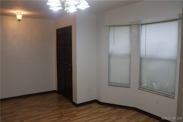 spare room featuring hardwood / wood-style flooring and a chandelier