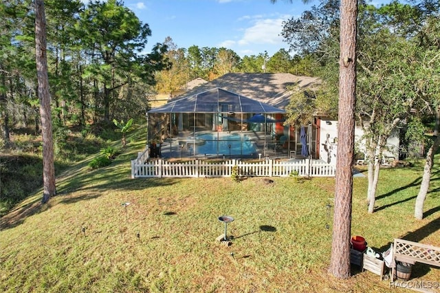 rear view of house with glass enclosure and a lawn