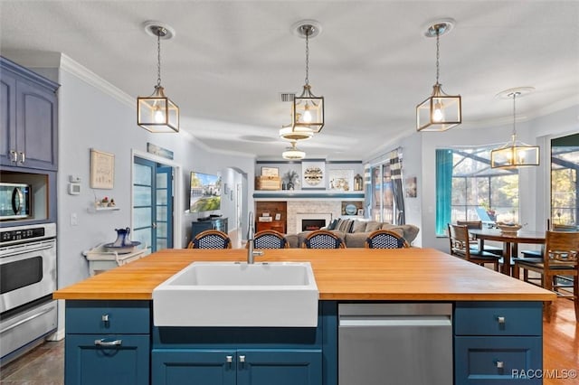 kitchen featuring wood counters, a center island with sink, and sink