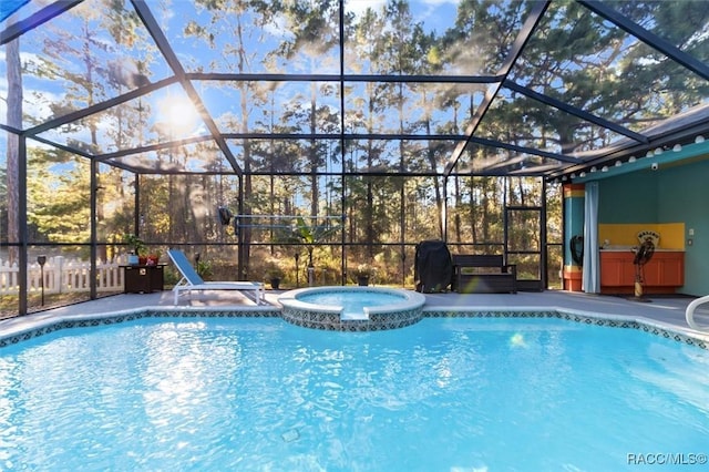 view of pool featuring glass enclosure, an in ground hot tub, and a patio area