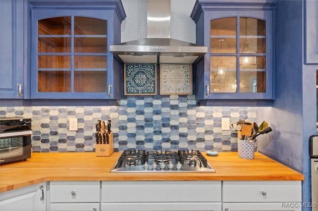 kitchen with decorative backsplash, butcher block countertops, stainless steel gas stovetop, and wall chimney exhaust hood