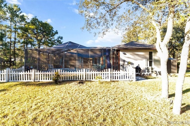 back of house with a patio, a yard, and glass enclosure