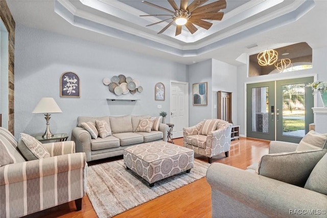 living room featuring wood-type flooring, ornamental molding, and a tray ceiling