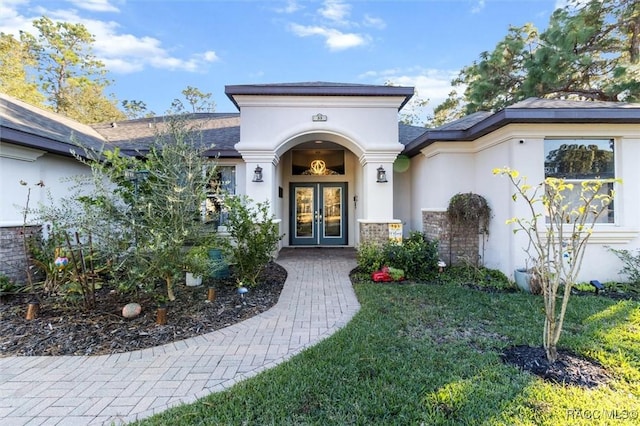 view of exterior entry featuring a lawn and french doors