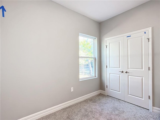 unfurnished bedroom with light colored carpet and a closet