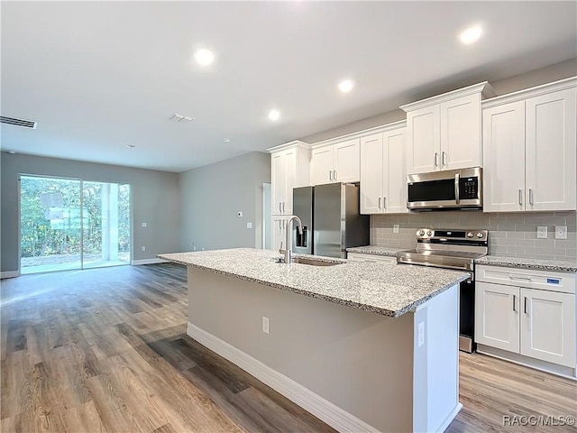 kitchen featuring white cabinetry, light hardwood / wood-style floors, an island with sink, and appliances with stainless steel finishes