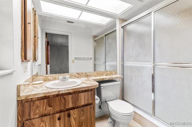 bathroom with a shower with door, vanity, and toilet