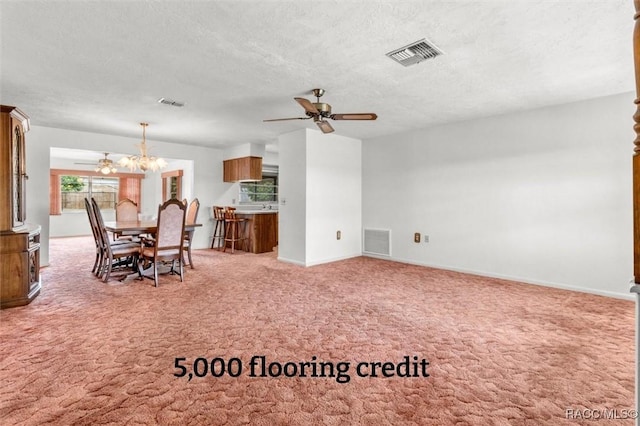 unfurnished living room featuring carpet, ceiling fan with notable chandelier, and a textured ceiling