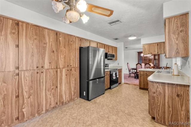 kitchen featuring sink, ceiling fan, appliances with stainless steel finishes, a textured ceiling, and kitchen peninsula