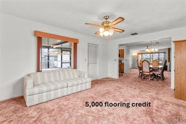 carpeted living room with ceiling fan with notable chandelier