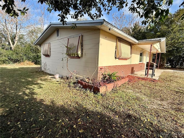 view of side of property featuring a patio area and a lawn