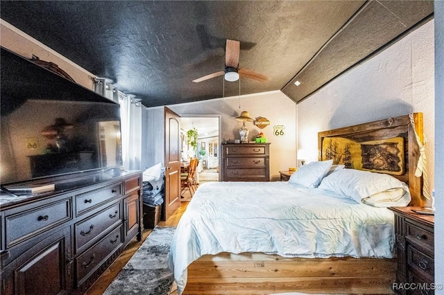 bedroom with ceiling fan, dark hardwood / wood-style flooring, vaulted ceiling, and a textured ceiling