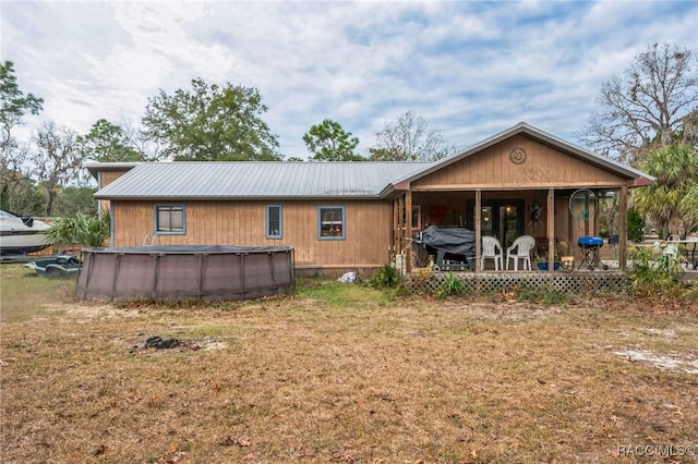 back of property featuring covered porch and a lawn