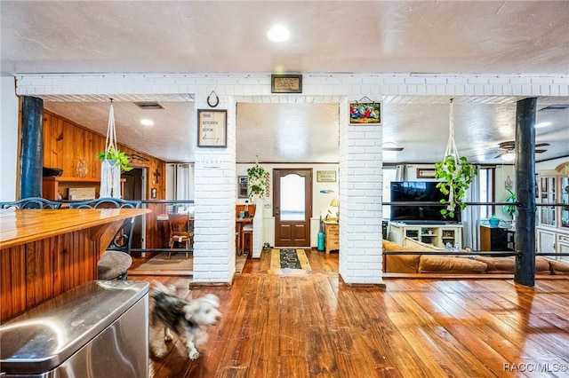 interior space featuring decorative columns, brick wall, ceiling fan, and wood-type flooring