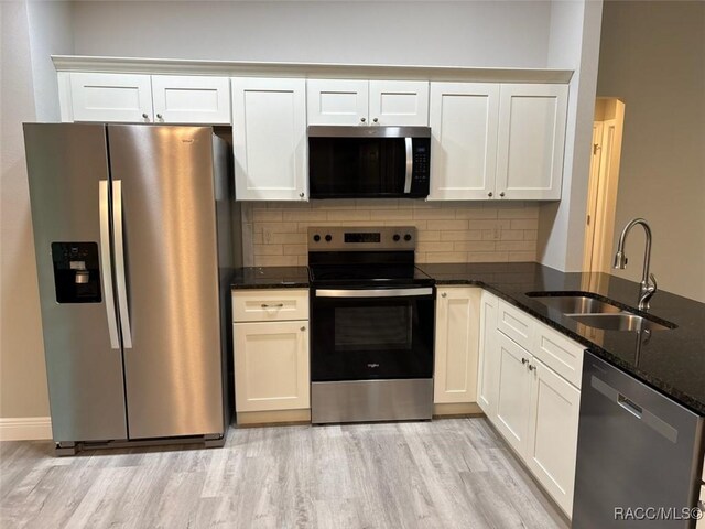 kitchen with stainless steel appliances, white cabinets, vaulted ceiling, a sink, and a peninsula