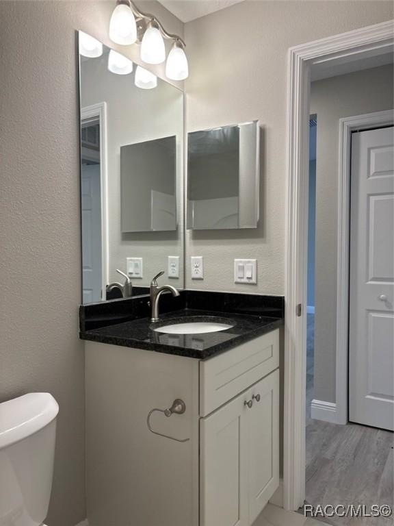 unfurnished bedroom featuring a closet, visible vents, a textured ceiling, wood finished floors, and baseboards