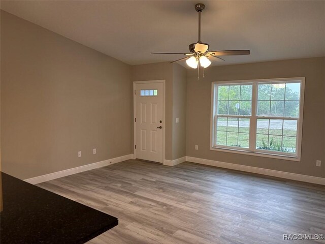 spare room with a textured ceiling, ceiling fan, wood finished floors, and baseboards