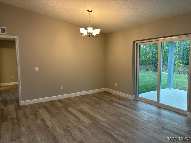 unfurnished room featuring a textured ceiling, wood finished floors, and baseboards