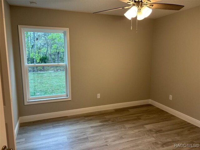 empty room with a textured ceiling, baseboards, and wood finished floors