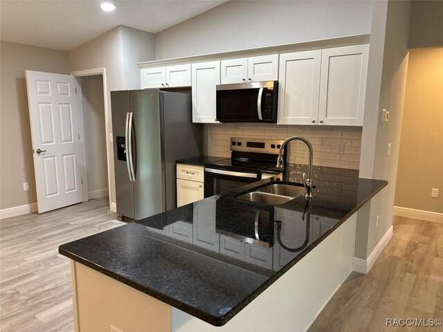 kitchen featuring stainless steel appliances, light wood-type flooring, a sink, and white cabinets