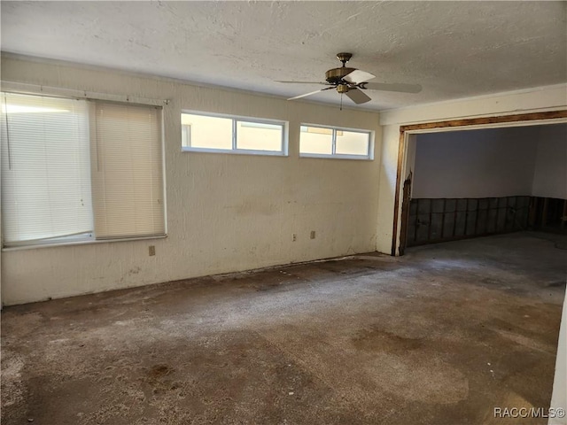 empty room with ceiling fan and a textured ceiling