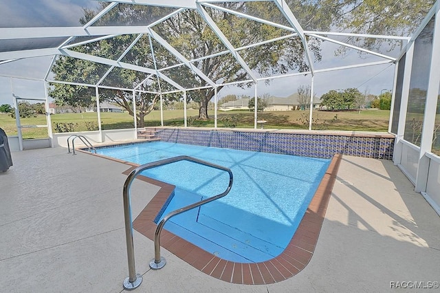 pool featuring glass enclosure, a lawn, and a patio