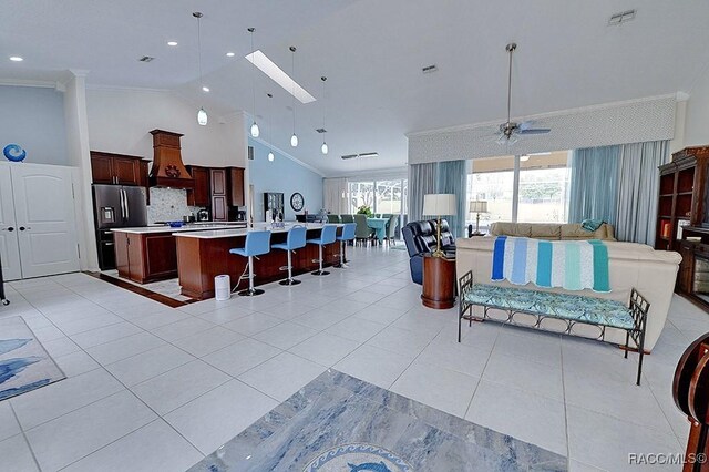 kitchen featuring visible vents, open floor plan, light countertops, a center island with sink, and crown molding