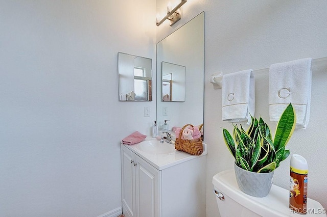 bathroom with toilet, baseboards, and vanity