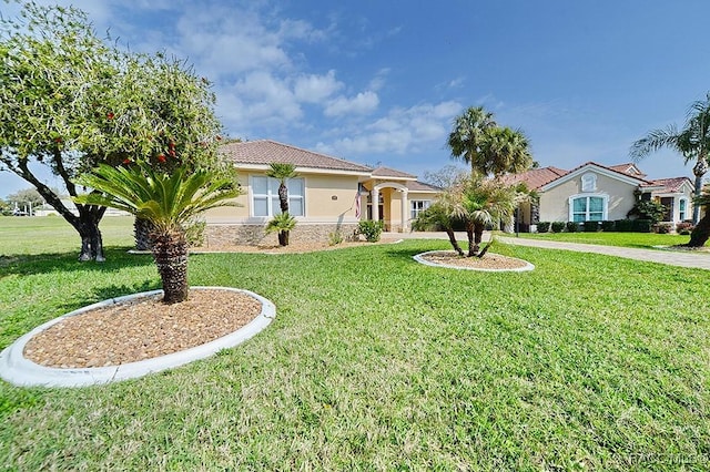 mediterranean / spanish home with stone siding, a tiled roof, a front lawn, and stucco siding