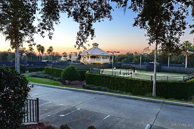 exterior space featuring a tennis court, a gazebo, and fence