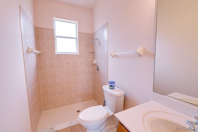 bathroom with toilet, tiled shower, and vanity