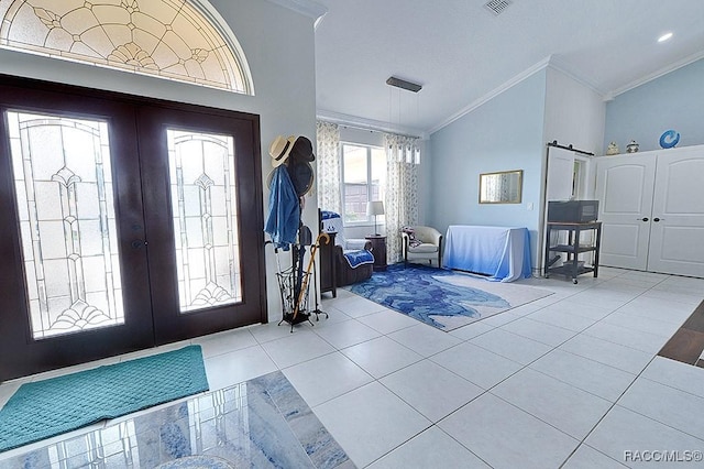 foyer entrance with lofted ceiling, tile patterned flooring, ornamental molding, and french doors