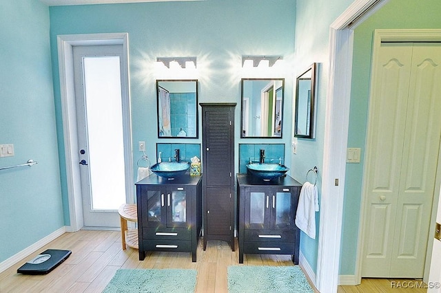 bathroom with two vanities, baseboards, and wood finished floors